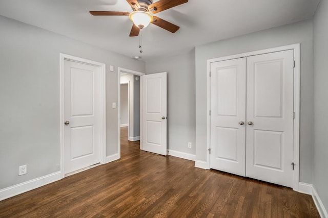 unfurnished bedroom with dark wood-style floors, a closet, a ceiling fan, and baseboards