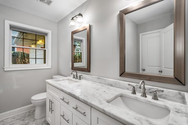 full bathroom with visible vents, double vanity, a sink, and toilet