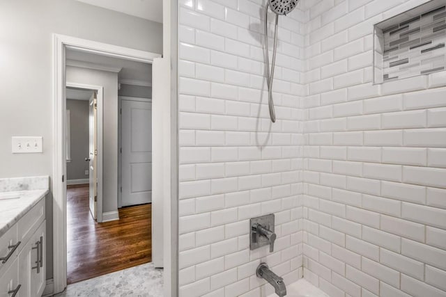 bathroom featuring baseboards, shower / bathing tub combination, wood finished floors, and vanity