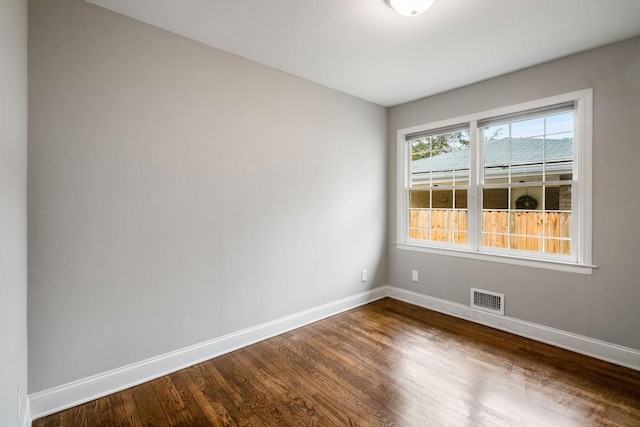 unfurnished room featuring baseboards, visible vents, and dark wood-type flooring