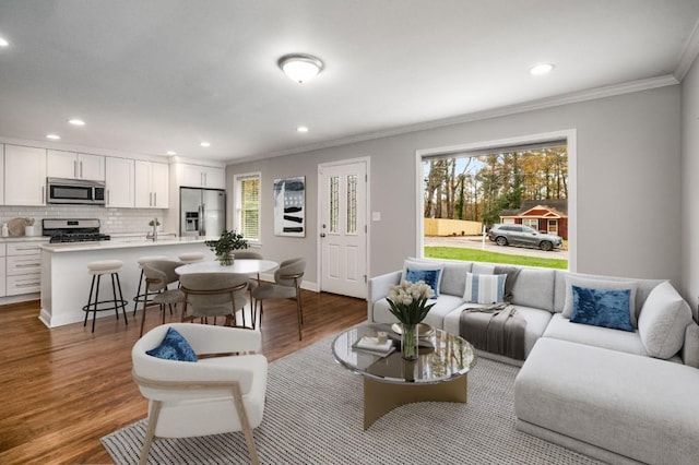 living area featuring plenty of natural light, crown molding, wood finished floors, and recessed lighting