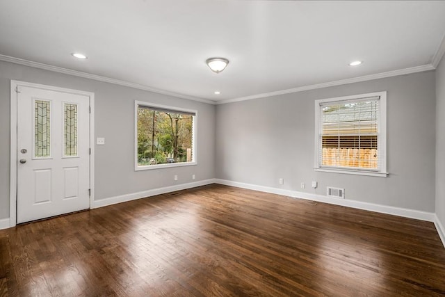 spare room with crown molding, wood finished floors, visible vents, and baseboards