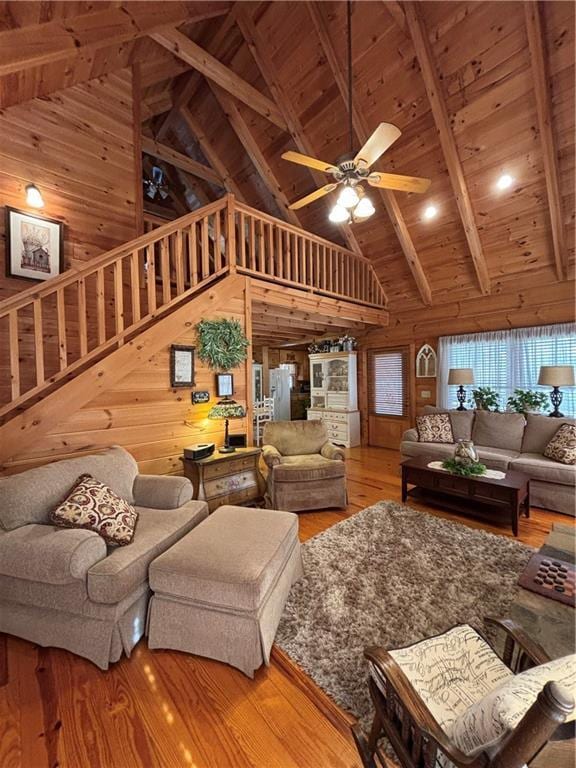 living room featuring hardwood / wood-style floors, beam ceiling, wooden walls, high vaulted ceiling, and wooden ceiling