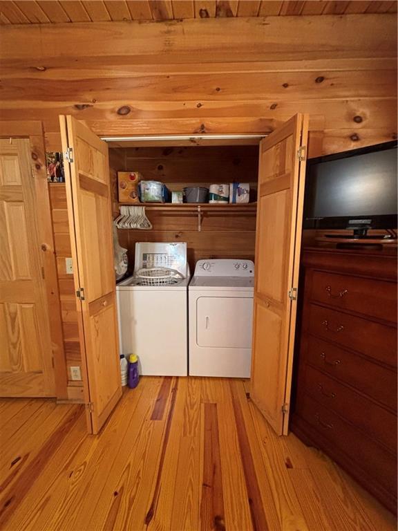 clothes washing area with light hardwood / wood-style floors, independent washer and dryer, and wooden ceiling