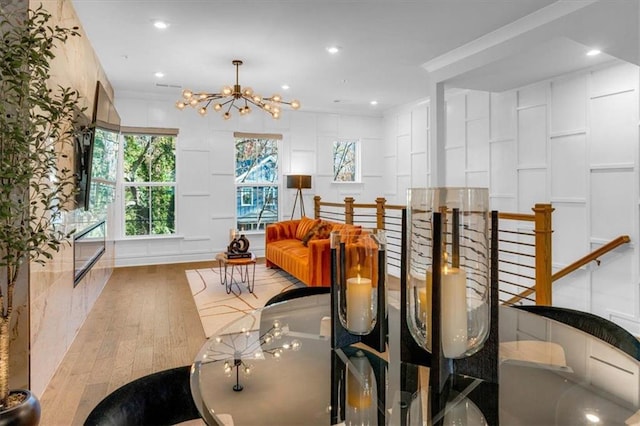 dining space featuring ornamental molding, a notable chandelier, and light hardwood / wood-style flooring