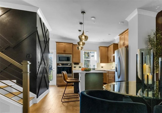 kitchen with a kitchen island, pendant lighting, a kitchen breakfast bar, light hardwood / wood-style floors, and stainless steel appliances