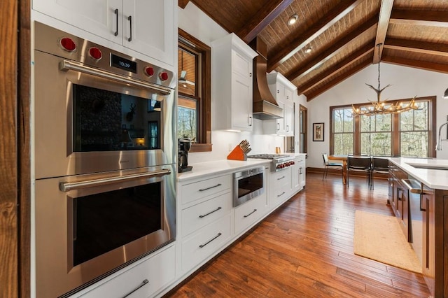 975 Blalock Lakes Dr, Newnan, GA 30263 - kitchen featuring dark wood-type flooring, vaulted ceiling with beams, custom exhaust hood, stainless steel appliances, and light countertops