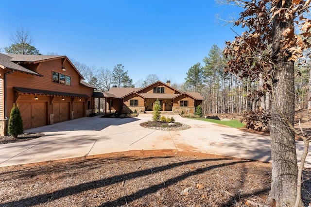 rustic home with a garage, concrete driveway, and stone siding