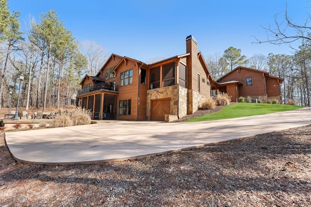 975 Blalock Lakes Dr, Newnan, GA 30263 - view of side of home with concrete driveway, a balcony, stone siding, a sunroom, and a chimney