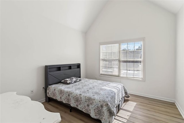 bedroom with high vaulted ceiling, baseboards, and wood finished floors