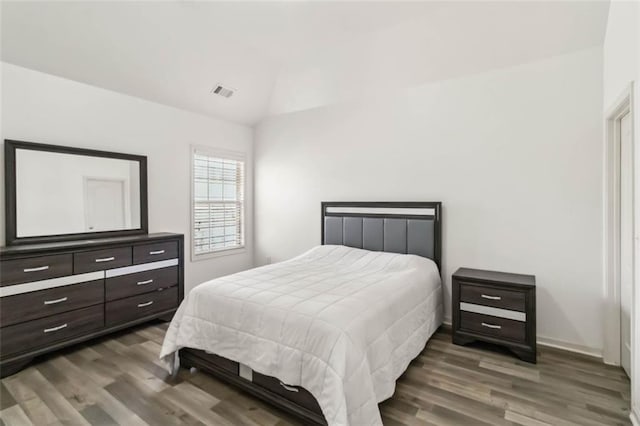 bedroom featuring dark wood finished floors, visible vents, and vaulted ceiling