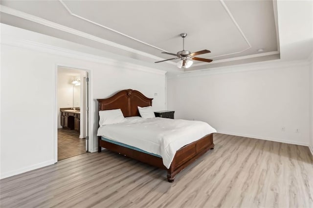 bedroom featuring light wood finished floors, a raised ceiling, and crown molding