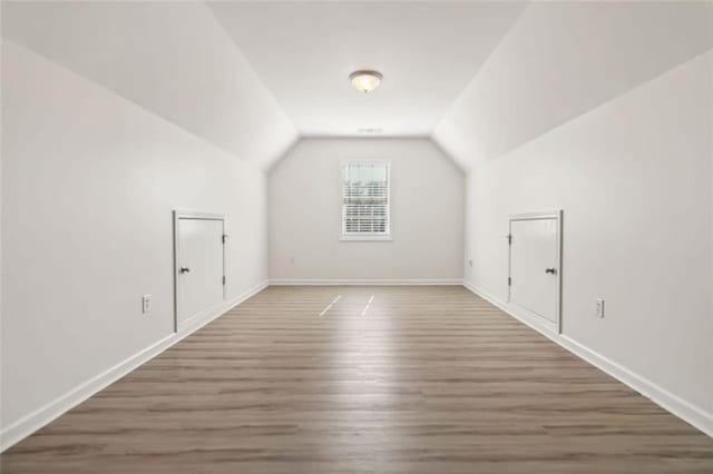 bonus room with baseboards, vaulted ceiling, and dark wood-type flooring