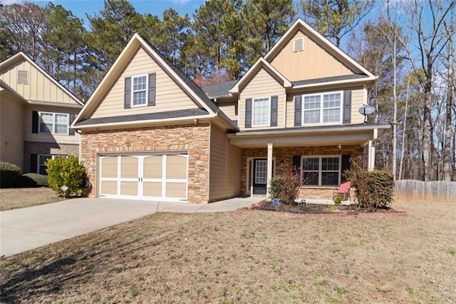 traditional-style home featuring driveway, stone siding, fence, and a front yard