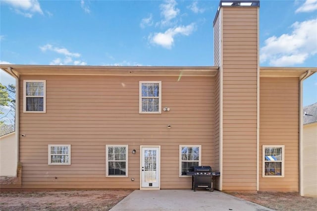 rear view of property featuring a patio and a chimney