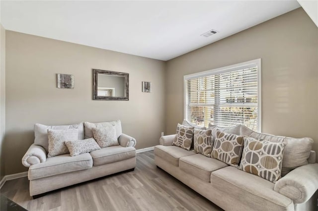 living area featuring visible vents, baseboards, and wood finished floors