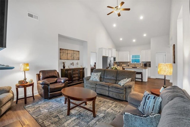 living room with visible vents, high vaulted ceiling, a ceiling fan, baseboards, and dark wood-style flooring