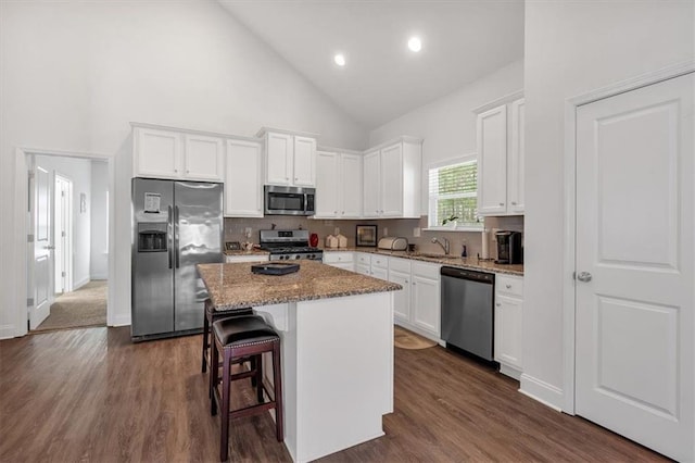 kitchen with backsplash, a kitchen island, white cabinets, stone countertops, and stainless steel appliances