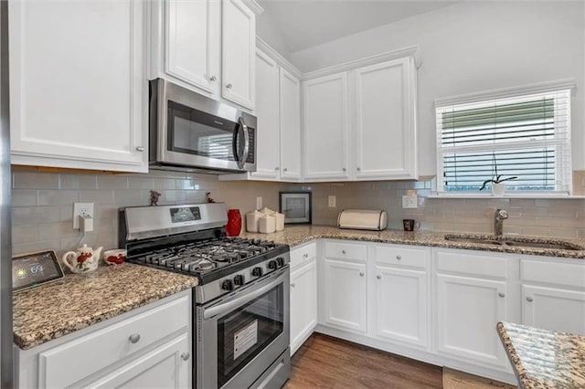 kitchen featuring a sink, light stone counters, backsplash, white cabinetry, and appliances with stainless steel finishes