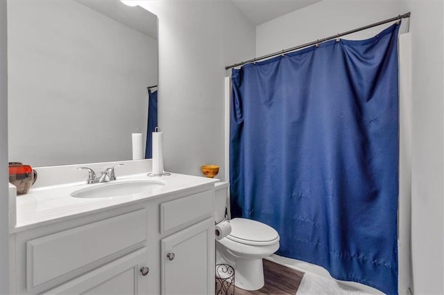 bathroom featuring a shower with curtain, toilet, wood finished floors, and vanity