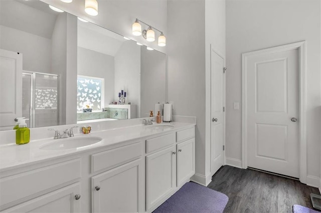 bathroom with double vanity, a shower stall, wood finished floors, and a sink