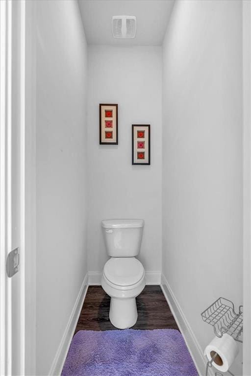 bathroom with toilet, wood finished floors, visible vents, and baseboards