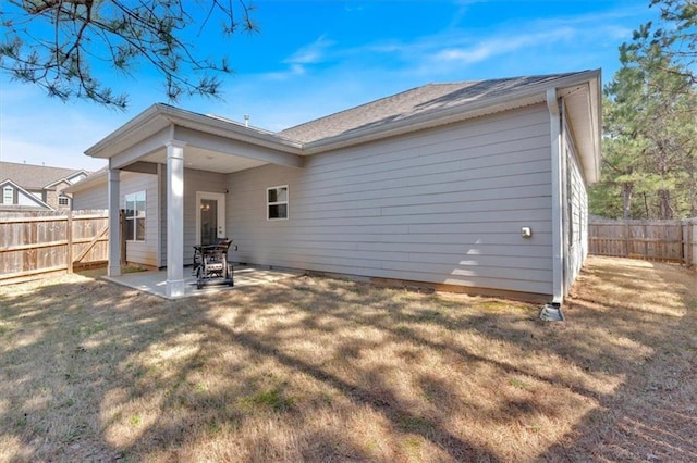 rear view of house with a patio, a fenced backyard, and a lawn