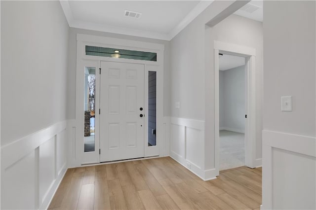 entryway with crown molding and light hardwood / wood-style floors