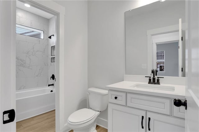 full bathroom with vanity, hardwood / wood-style floors, tiled shower / bath, and toilet