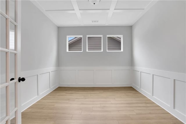 empty room featuring coffered ceiling and light hardwood / wood-style floors