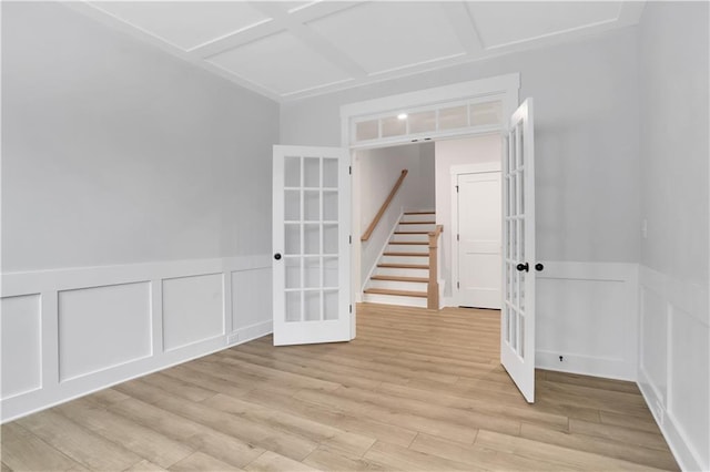 spare room featuring french doors, coffered ceiling, and light wood-type flooring