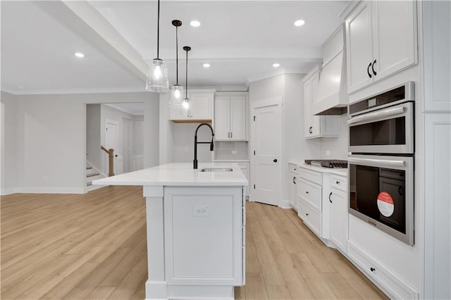 kitchen with decorative light fixtures, sink, white cabinets, a kitchen island with sink, and stainless steel appliances