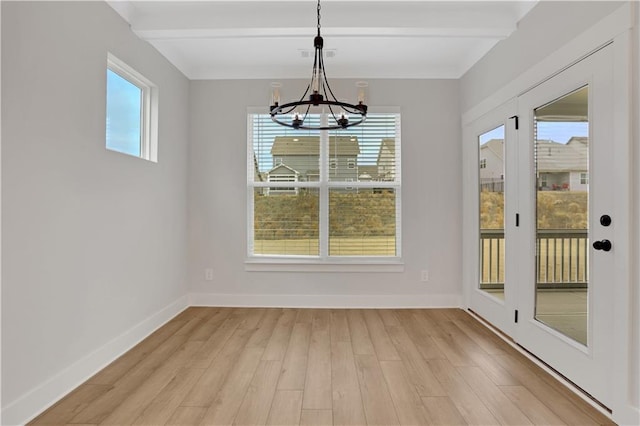 unfurnished dining area with a healthy amount of sunlight, beam ceiling, and light hardwood / wood-style floors