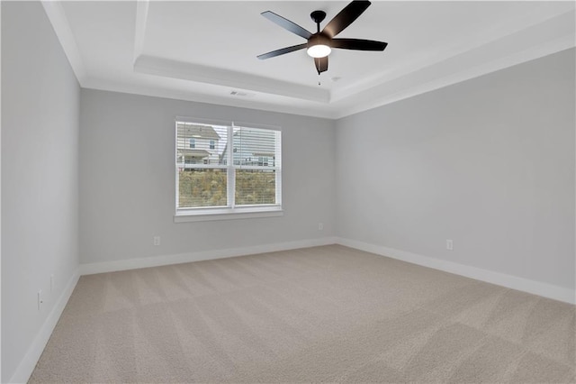 carpeted spare room featuring a raised ceiling and ceiling fan