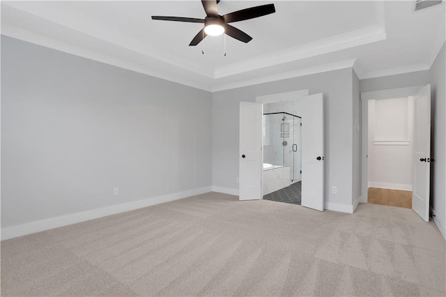 unfurnished bedroom with crown molding, light colored carpet, a raised ceiling, and ensuite bath