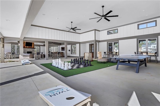 interior space featuring ceiling fan, an outdoor living space with a fireplace, and a patio area