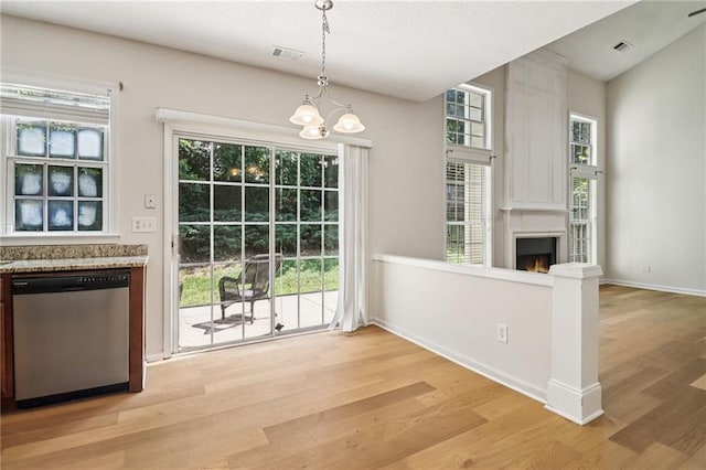 605 Alstonefield Dr, Alpharetta, GA 30004 - unfurnished dining area with light wood finished floors, a lit fireplace, a chandelier, and plenty of natural light