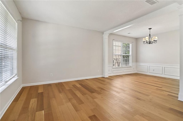 605 Alstonefield Dr, Alpharetta, GA 30004 - unfurnished room featuring ornate columns, light wood finished floors, a chandelier, and wainscoting