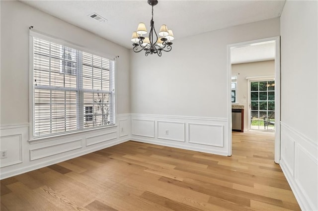 605 Alstonefield Dr, Alpharetta, GA 30004 - unfurnished dining area with a chandelier, healthy amount of natural light, light wood-style floors, a decorative wall, and wainscoting