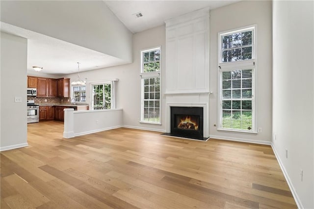 605 Alstonefield Dr, Alpharetta, GA 30004 - unfurnished living room featuring light wood-style floors, a large fireplace, and a chandelier