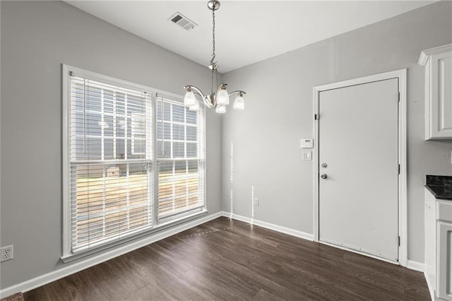 unfurnished dining area with dark wood finished floors, a notable chandelier, baseboards, and visible vents