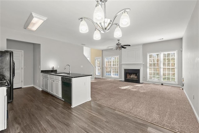 kitchen with dark countertops, black appliances, a large fireplace, dark wood-style floors, and white cabinetry