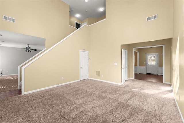 unfurnished living room with visible vents, carpet, and a towering ceiling