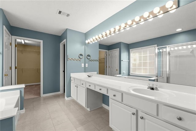 bathroom featuring visible vents, a shower stall, baseboards, double vanity, and a sink