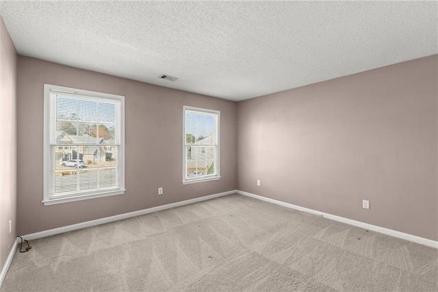 spare room with visible vents, light colored carpet, and baseboards