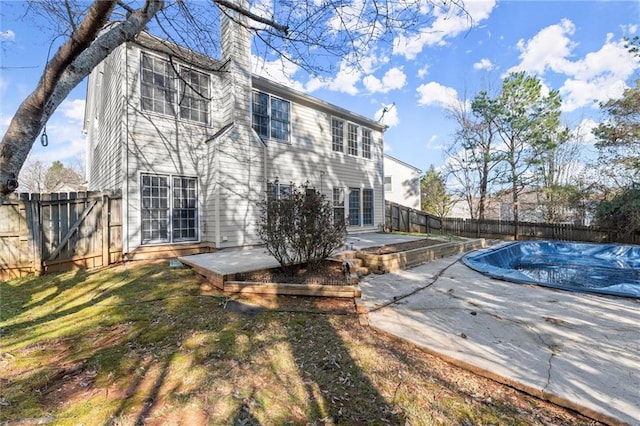 rear view of property with a patio area, a fenced backyard, and a chimney