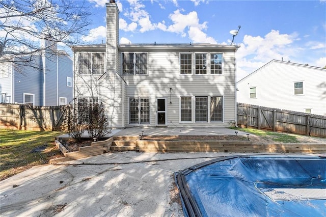 rear view of house featuring a fenced in pool, a patio, a fenced backyard, and a chimney