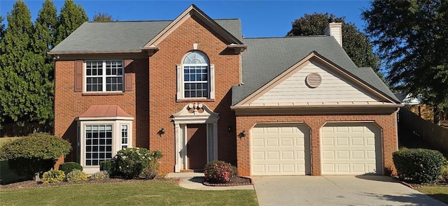 view of front of house with a garage, brick siding, driveway, and a chimney