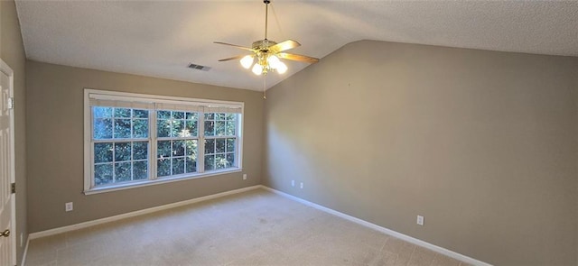 empty room featuring baseboards, visible vents, light colored carpet, vaulted ceiling, and a textured ceiling