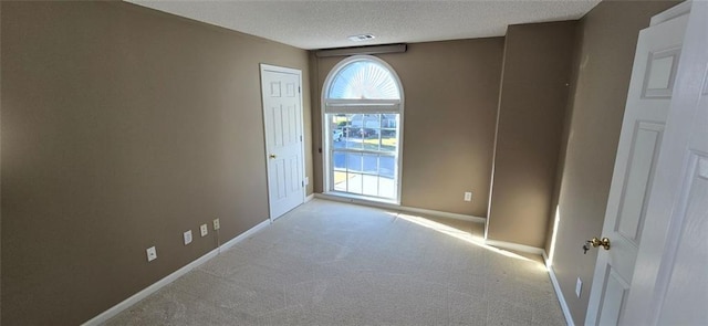 empty room with a textured ceiling, carpet, visible vents, and baseboards